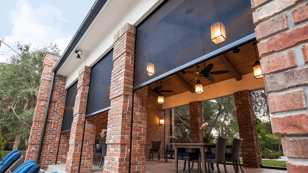 A large outdoor seating area with high ceilings, brick support columns, and retractable weather protection screens.