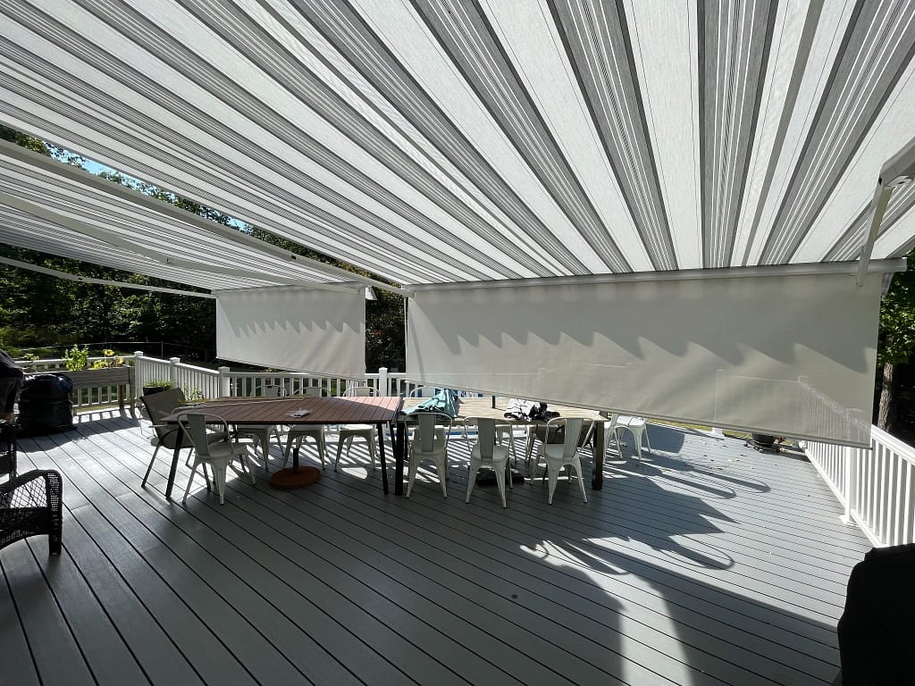 A well-shaded view of a large porch from beneath a striped awning