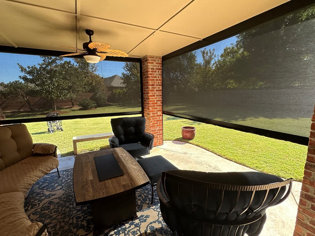 A patio shaded by retractable screens, left partially open, creating a comfortable outdoor seating area that is safe from bugs, heat, and wind.
